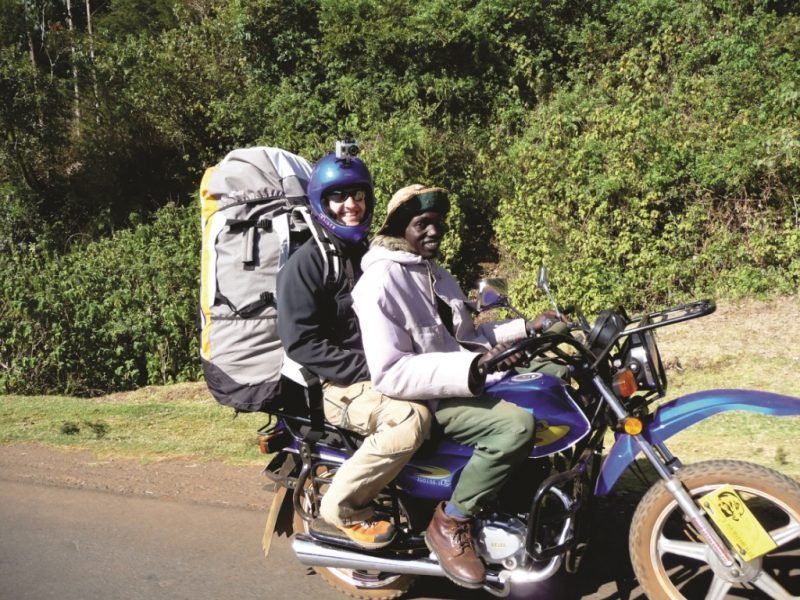 A pilot riding back to the lodge on a boda boda with his wing